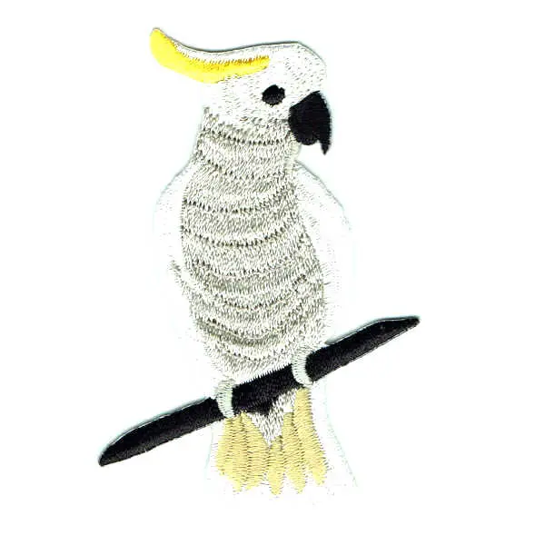 Embroidered patch of a sulphur crested cockatoo sitting on a tree branch